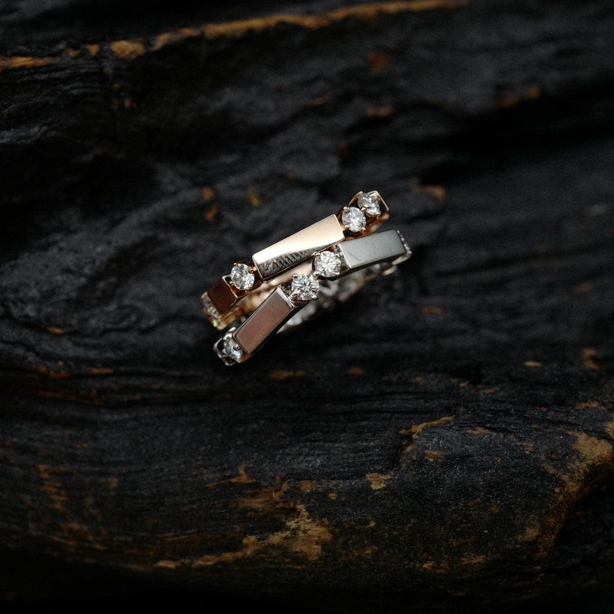 Kanpoj Verso stacked rings in pink and white gold, on dark wood
